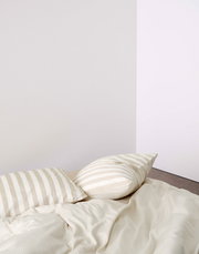 Bettwäsche-Set mit beigen und weißen Streifen, bestehend aus einem Kissenbezug und einer Bettdecke, aus der Perspektive von oben fotografiert.