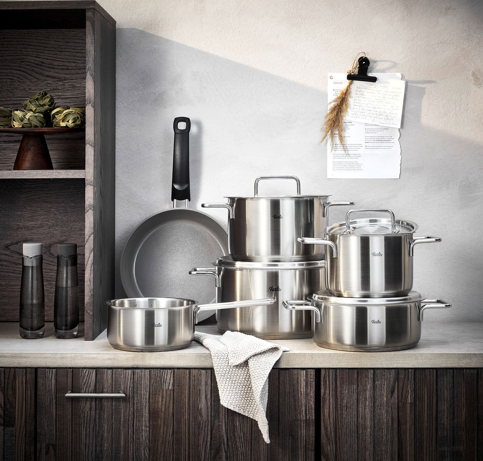 Fissler Topfset 5-tlg. PURE + Gratis Bratpfanne Ceratal 24cm Edelstahl-Topfset mit fünf Teilen und einer gratis Pfanne, frontal auf einer Küchenarbeitsplatte präsentiert.