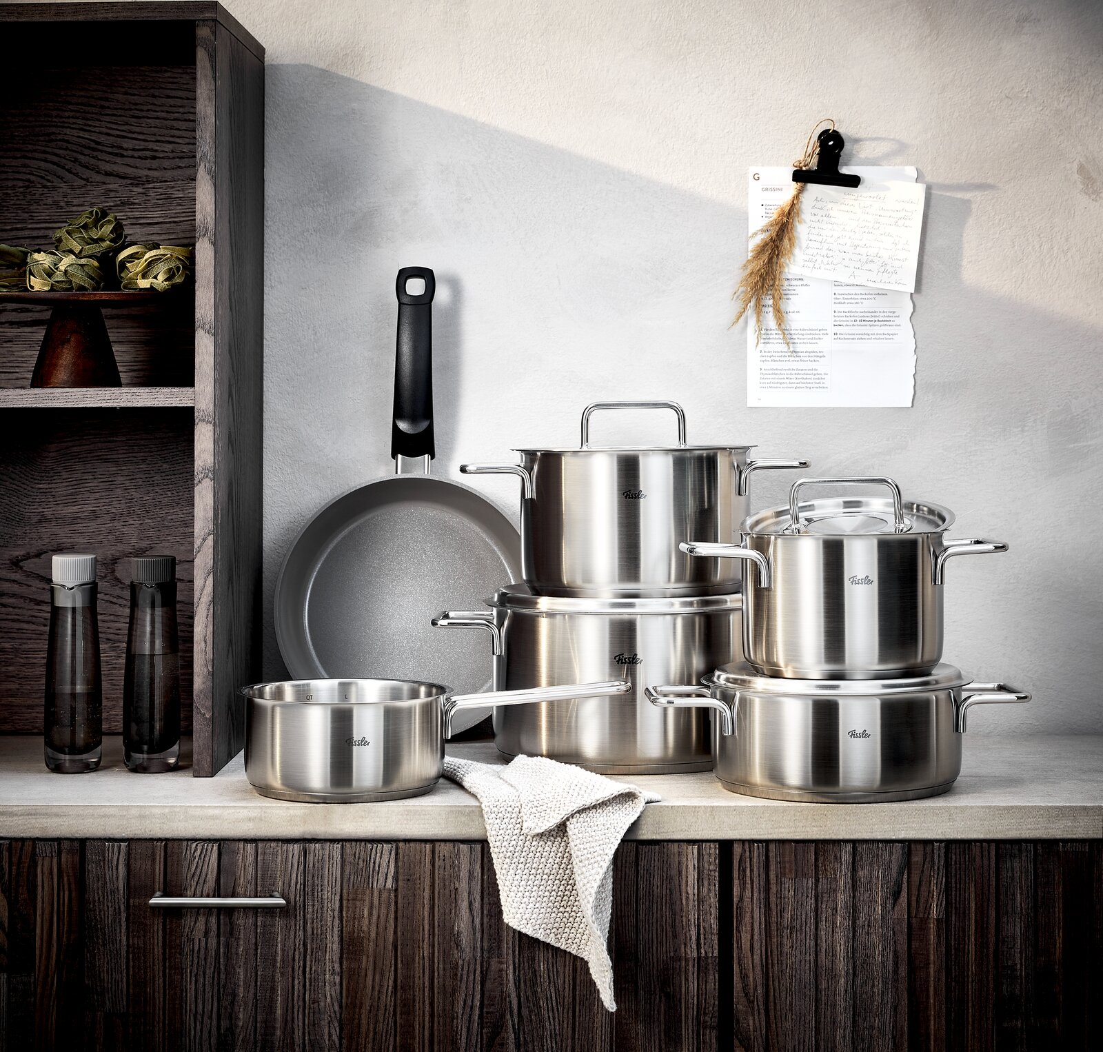 Fissler Topfset 5-tlg. PURE + Gratis Bratpfanne Ceratal 24cm Edelstahl-Topfset mit fünf Teilen und einer gratis Pfanne, frontal auf einer Küchenarbeitsplatte präsentiert.