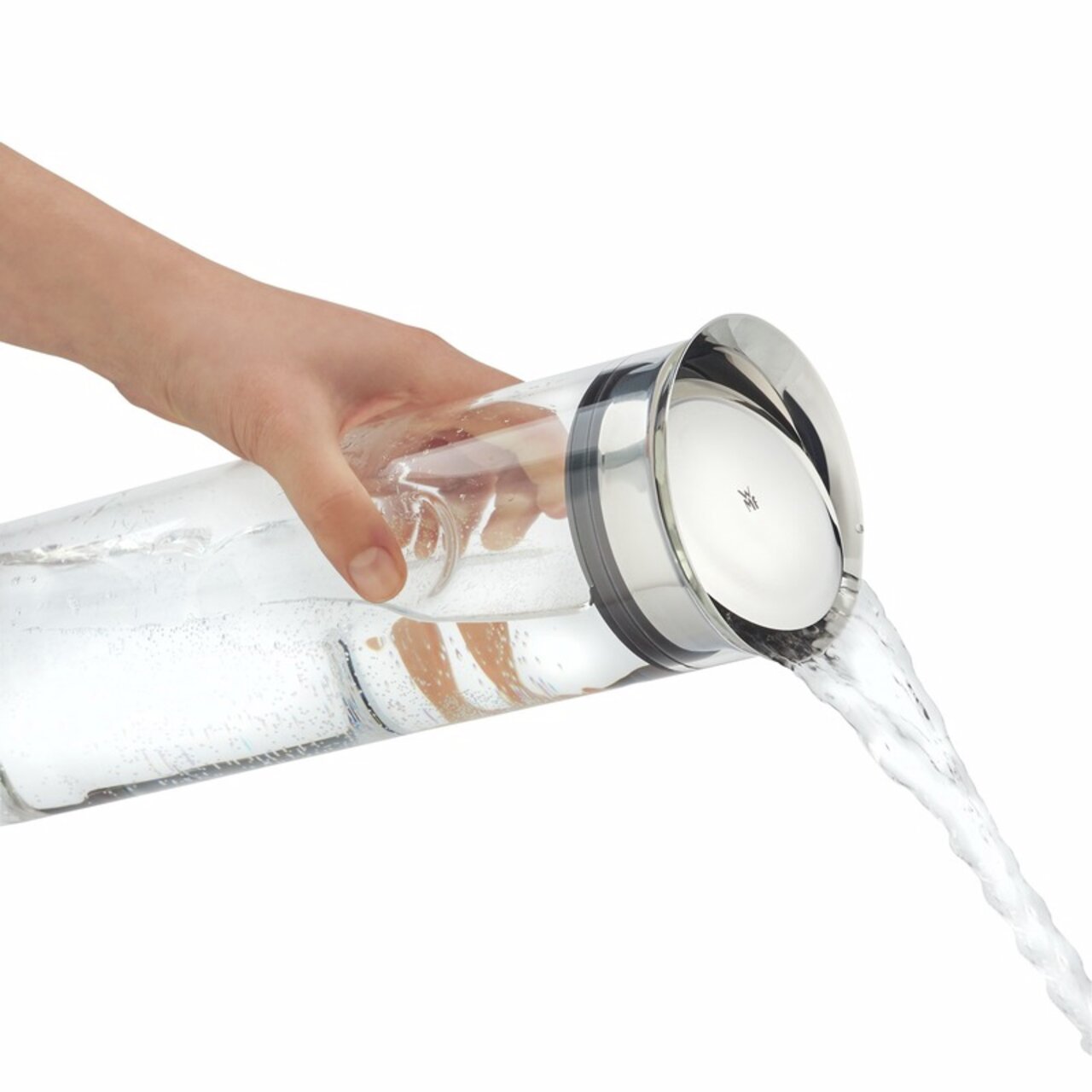 Hand gießt Wasser aus einer eleganten Wasserkaraffe mit Edelstahlverschluss, seitliche Perspektive