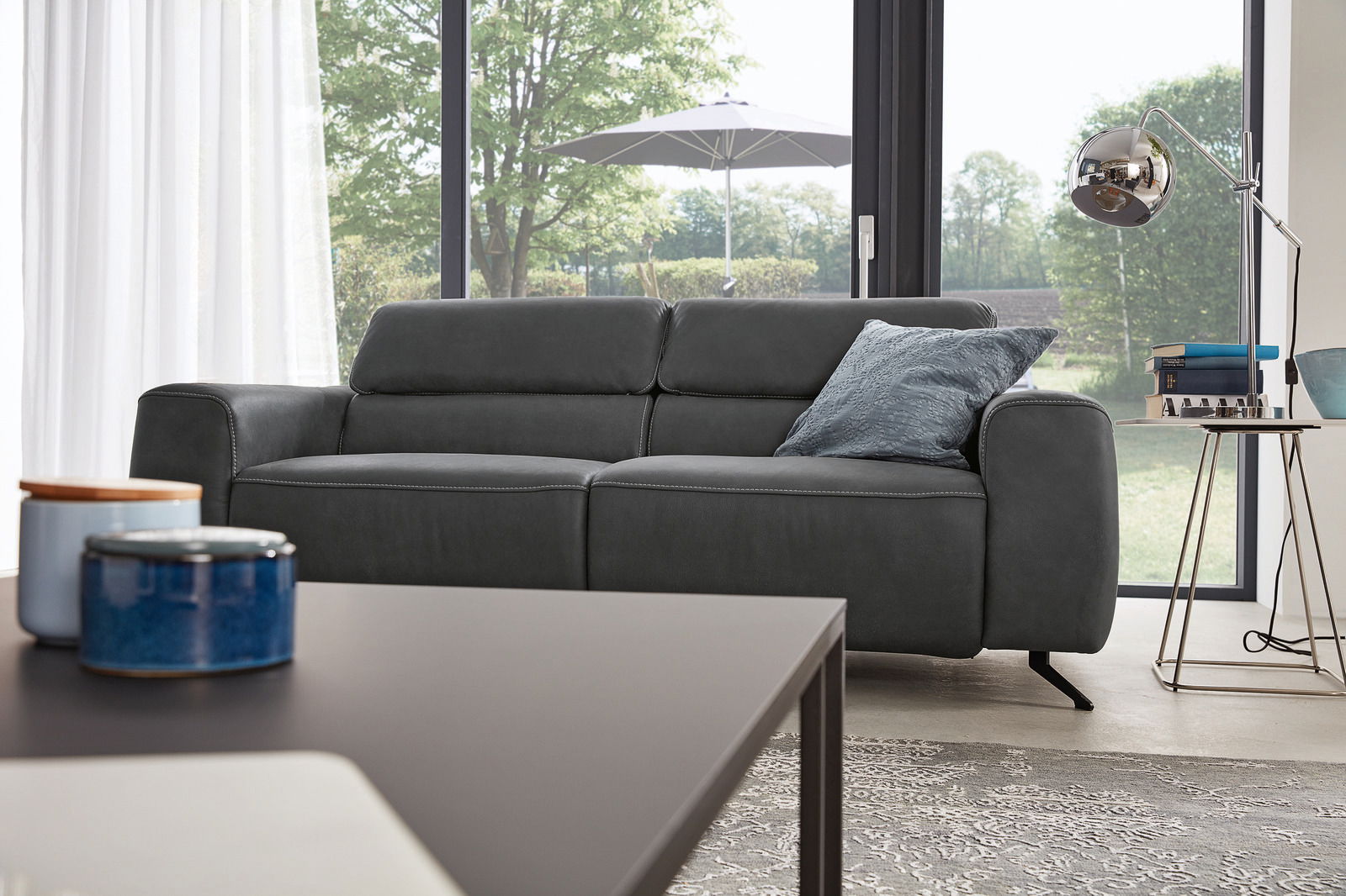 Modernes 2,5-Sitzer Sofa in dunklem Stoff, seitliche Perspektive, mit Kissen und stilvoller Umgebung.