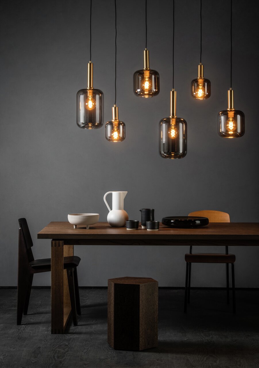 Moderne Pendelleuchten aus Glas und Metall in einem stilvollen Esszimmer, seitliche Perspektive