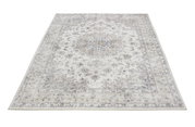 Tapijt in zachte beige- en grijstinten met een bloemmotief, gefotografeerd vanuit vogelperspectief.