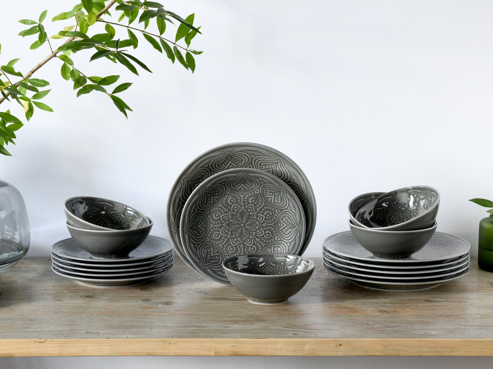 Creatable Tellerset 18-tlg ORIENT MANDALA Graues Keramik-Geschirrset mit dekorativem Mandala-Relief (Teller und Schalen) auf Holztisch vor hellem Hintergrund, Perspektive: frontale Ansicht auf Augenhöhe