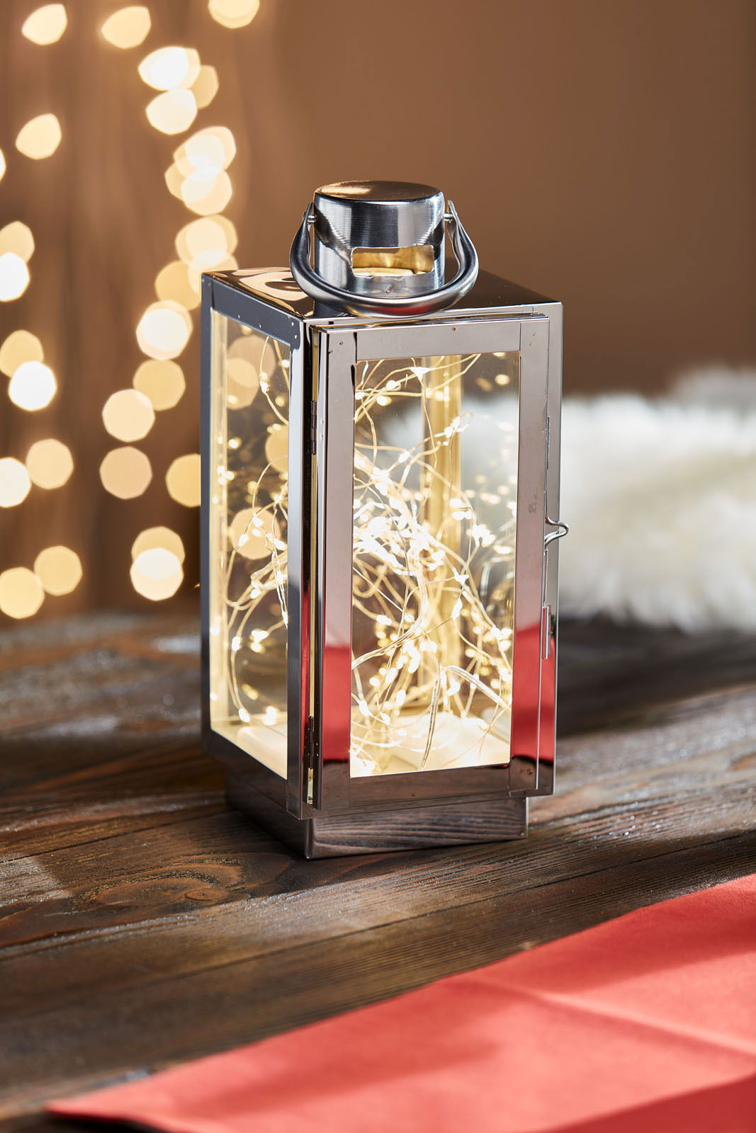 Edelstahl Laterne mit Lichterkette auf einem Holztisch, seitliche Perspektive