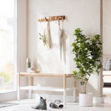 Wandgarderobe aus Holz mit Haken, an denen eine Tasche und ein Regenschirm hängen, im Vordergrund eine Bank und ein grüner Pflanzenkübel, seitliche Perspektive