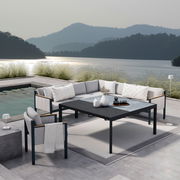 Moderne Lounge-Möbel auf einer Terrasse mit Seeblick, bestehend aus einem Ecksofa, einem Sessel und einem Gartentisch. Perspektive von schräg oben.