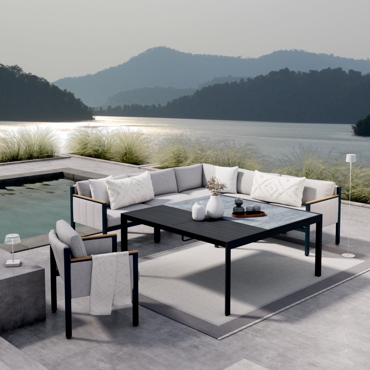 Moderne loungemeubels op een terras met uitzicht op het meer, bestaande uit een hoekbank, een fauteuil en een tuintafel. Aanzicht van schuin bovenaf.