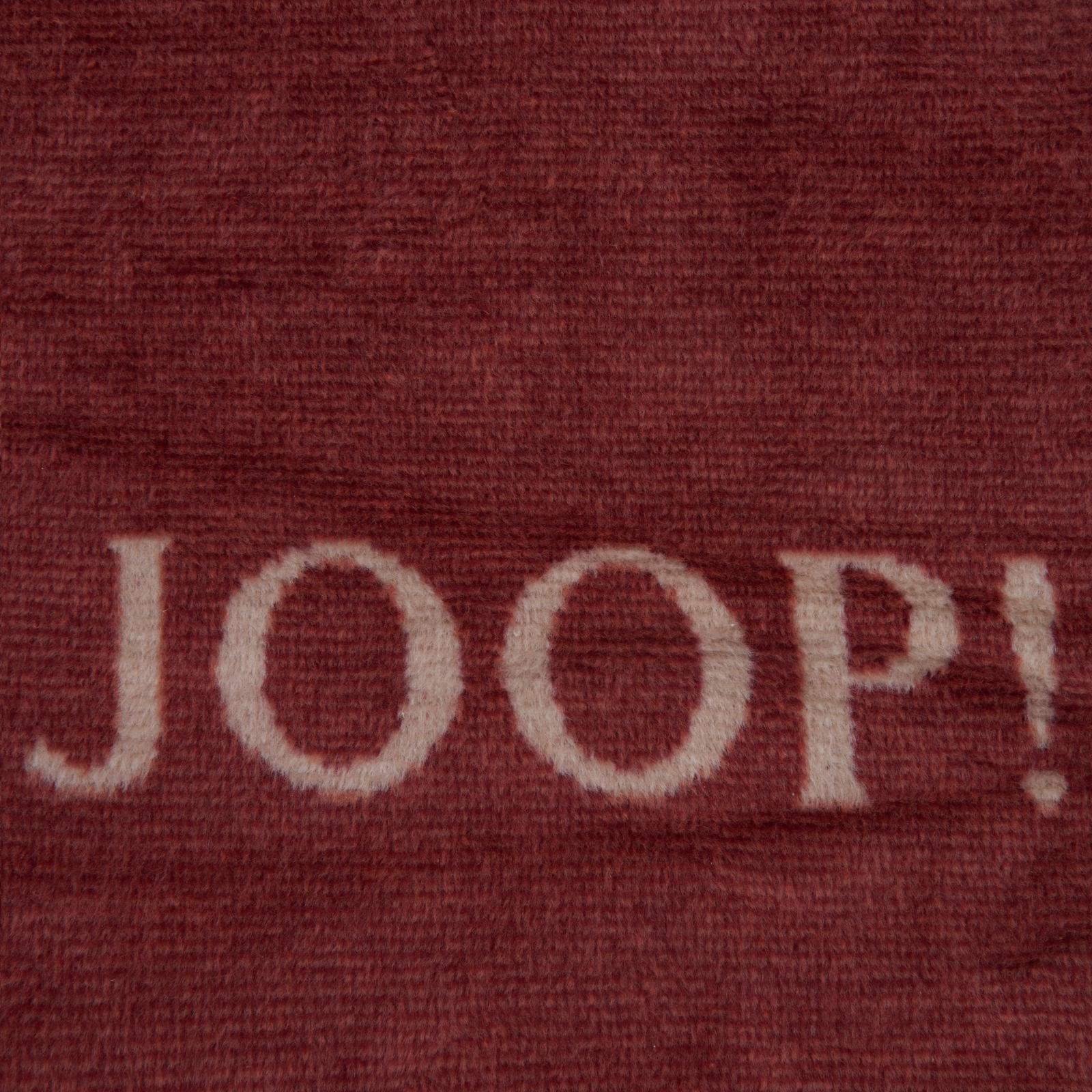 Nahaufnahme einer roten Decke mit dem weißen Schriftzug 'JOOP!'