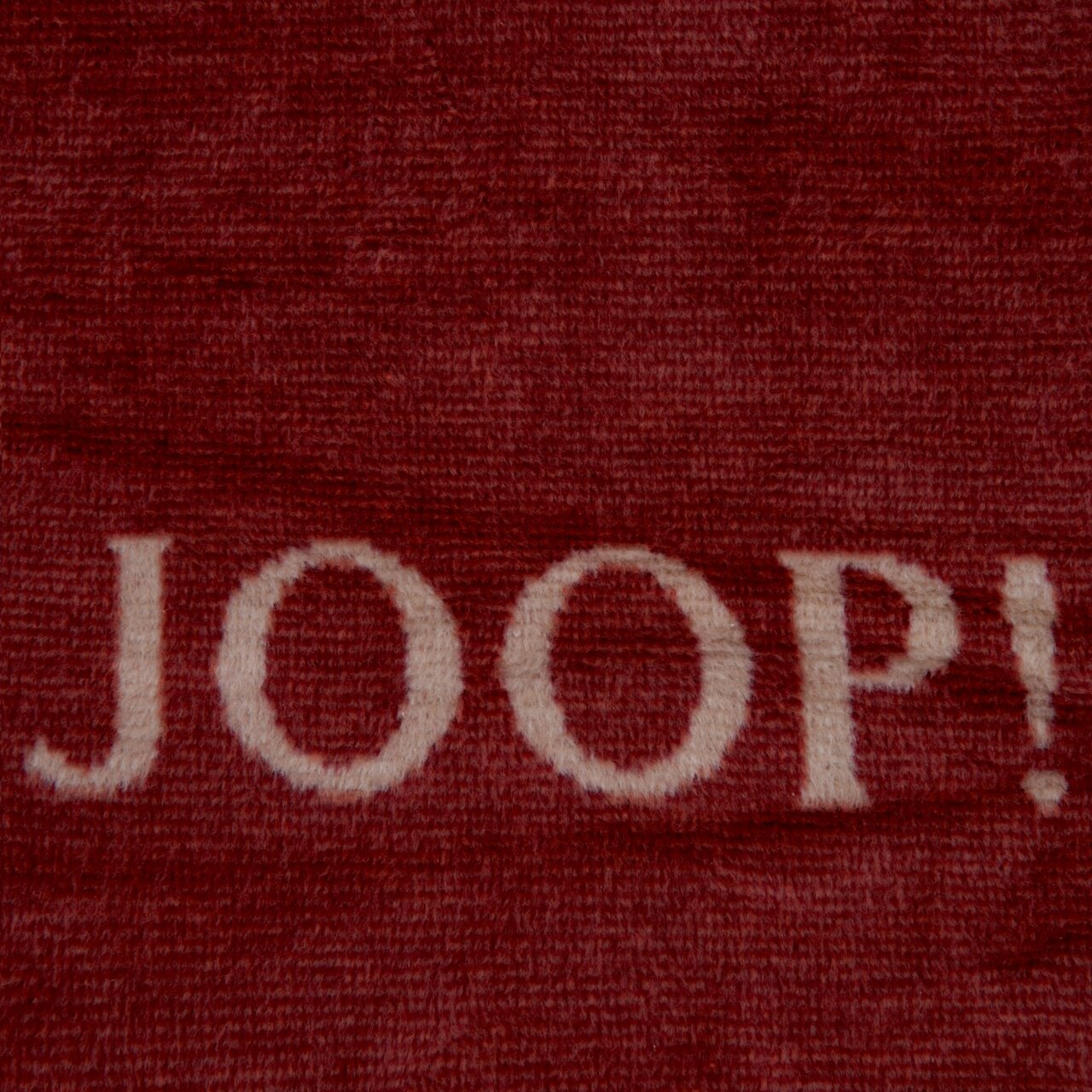 Nahaufnahme einer roten Decke mit dem weißen Schriftzug 'JOOP!'