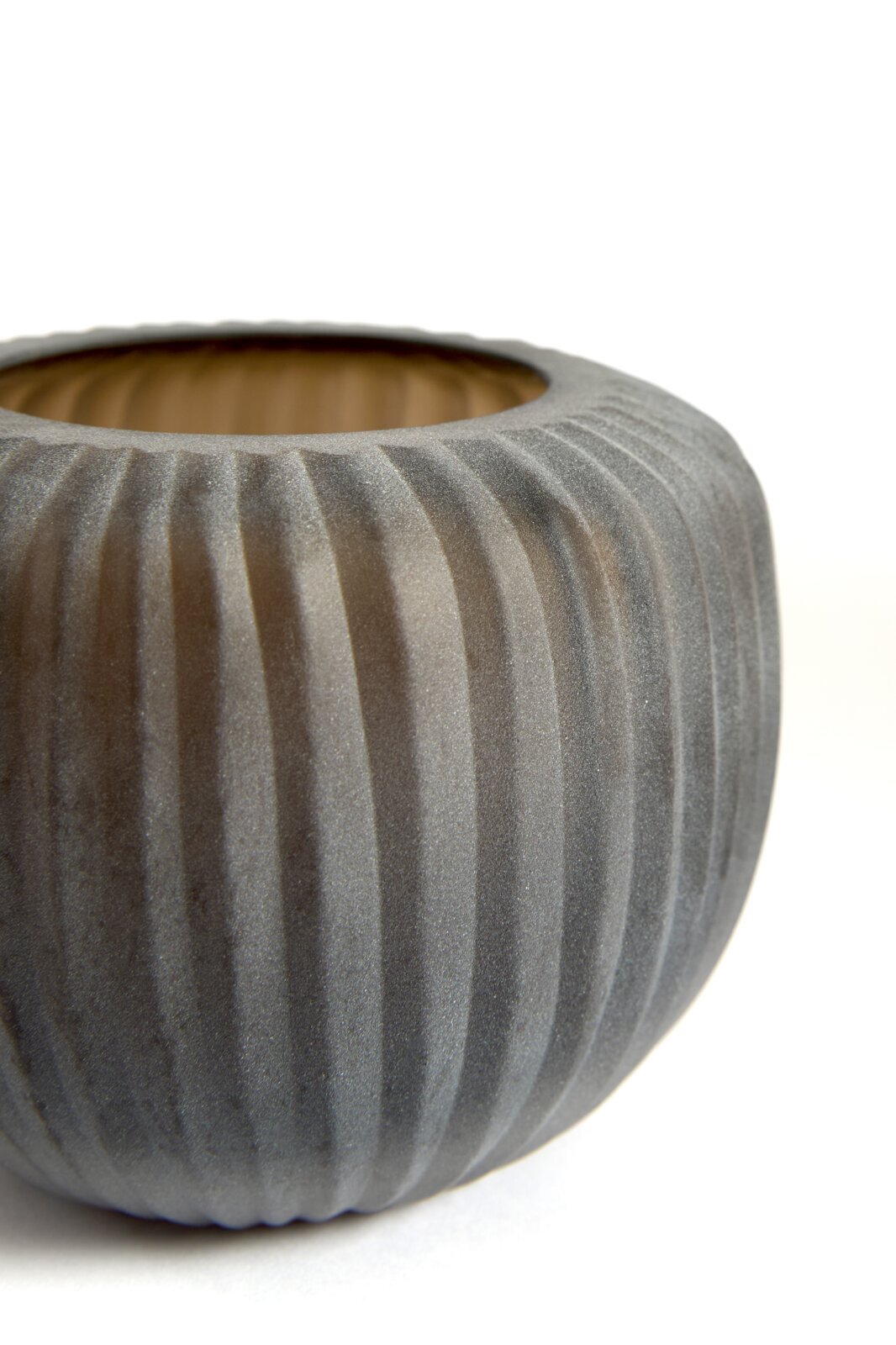 Close-up vanuit licht bovenaanzicht van een ronde, donkergrijze bloempot met verticale ribbelstructuur en warme houtkleurige binnenzijde tegen een witte achtergrond.