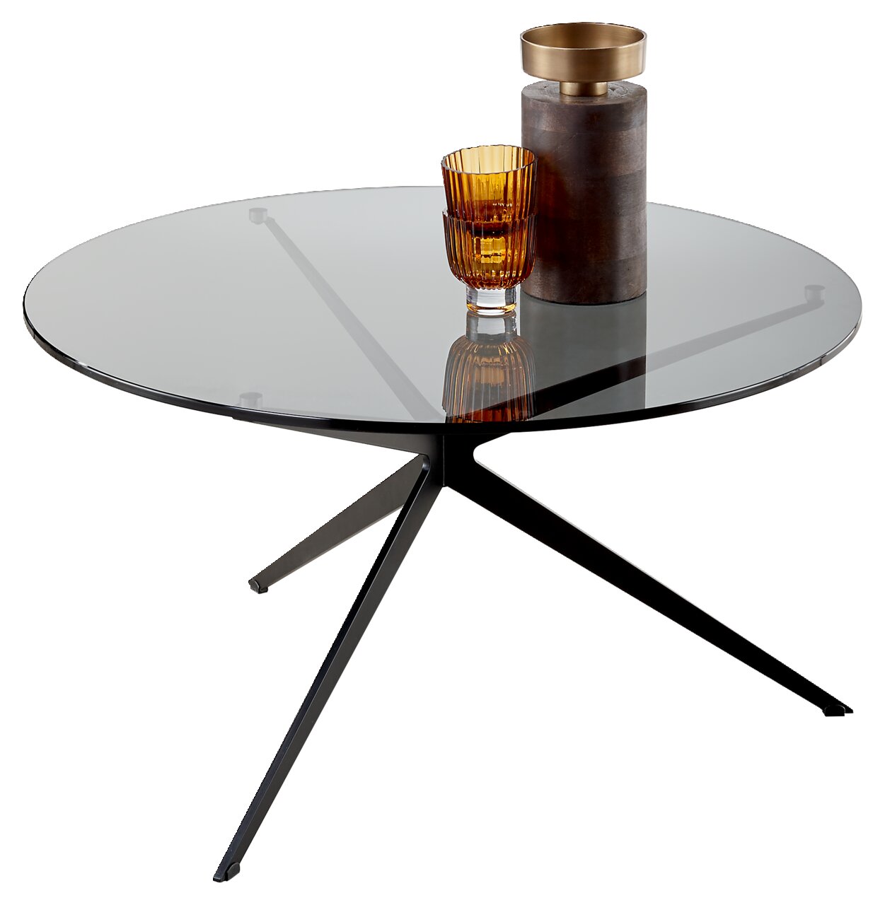 Runder Couchtisch mit Glasplatte und dreibeinigem Metallgestell, seitliche Perspektive, dekoriert mit einem goldenen Glas und einer Vase.