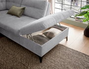 Graues Sofa mit Stauraum, geöffnet, von schräg oben fotografiert. Ein Kissen liegt auf der Sitzfläche.