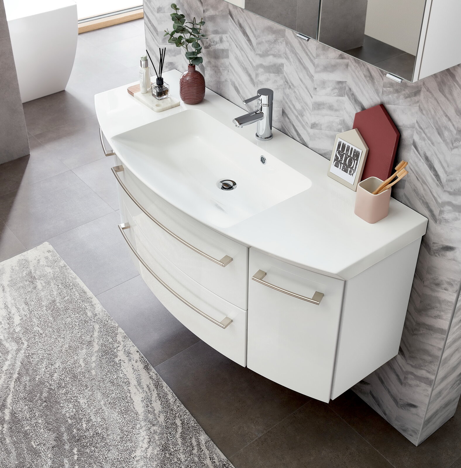 Moderne Badkombination mit weißem Waschbecken und Unterschrank, von oben fotografiert, mit stilvollen Accessoires dekoriert.