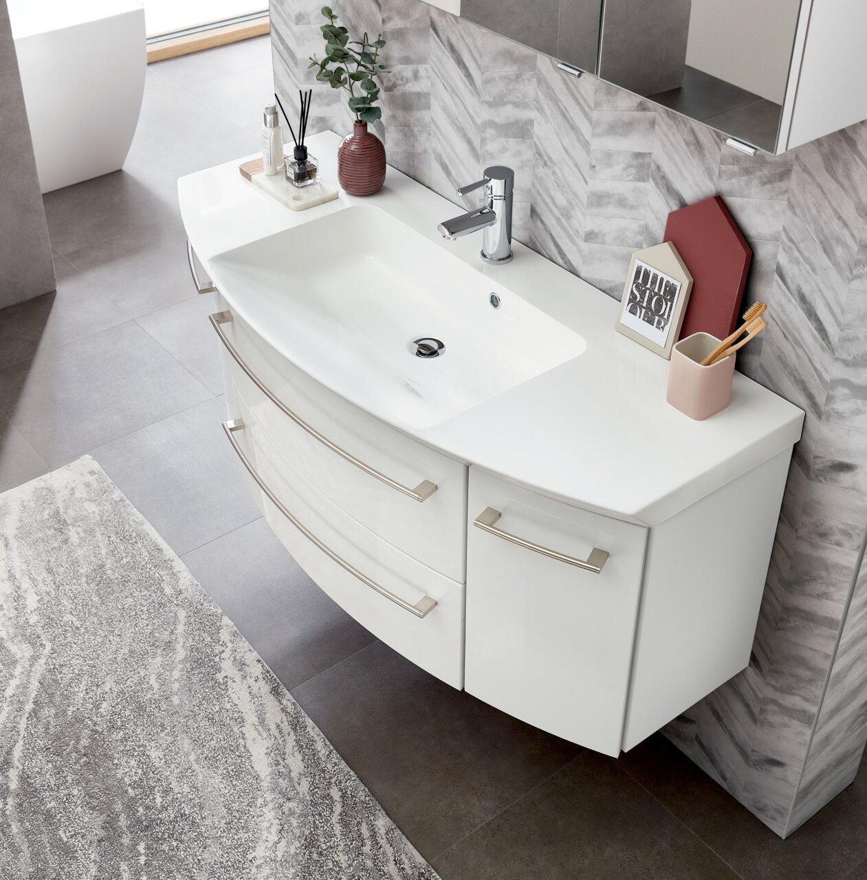 Moderne Badkombination mit weißem Waschbecken und Unterschrank, von oben fotografiert, mit stilvollen Accessoires dekoriert.