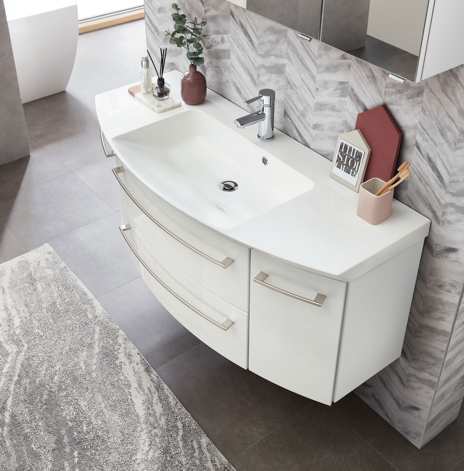 Moderne Badkombination mit weißem Waschbecken und Unterschrank, von oben fotografiert, mit stilvollen Accessoires dekoriert.