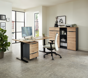 Moderner Büroraum mit Voleo E-Schreibtisch DETROIT in Holzoptik, Rollcontainer und ergonomischem Bürostuhl, seitliche Perspektive.