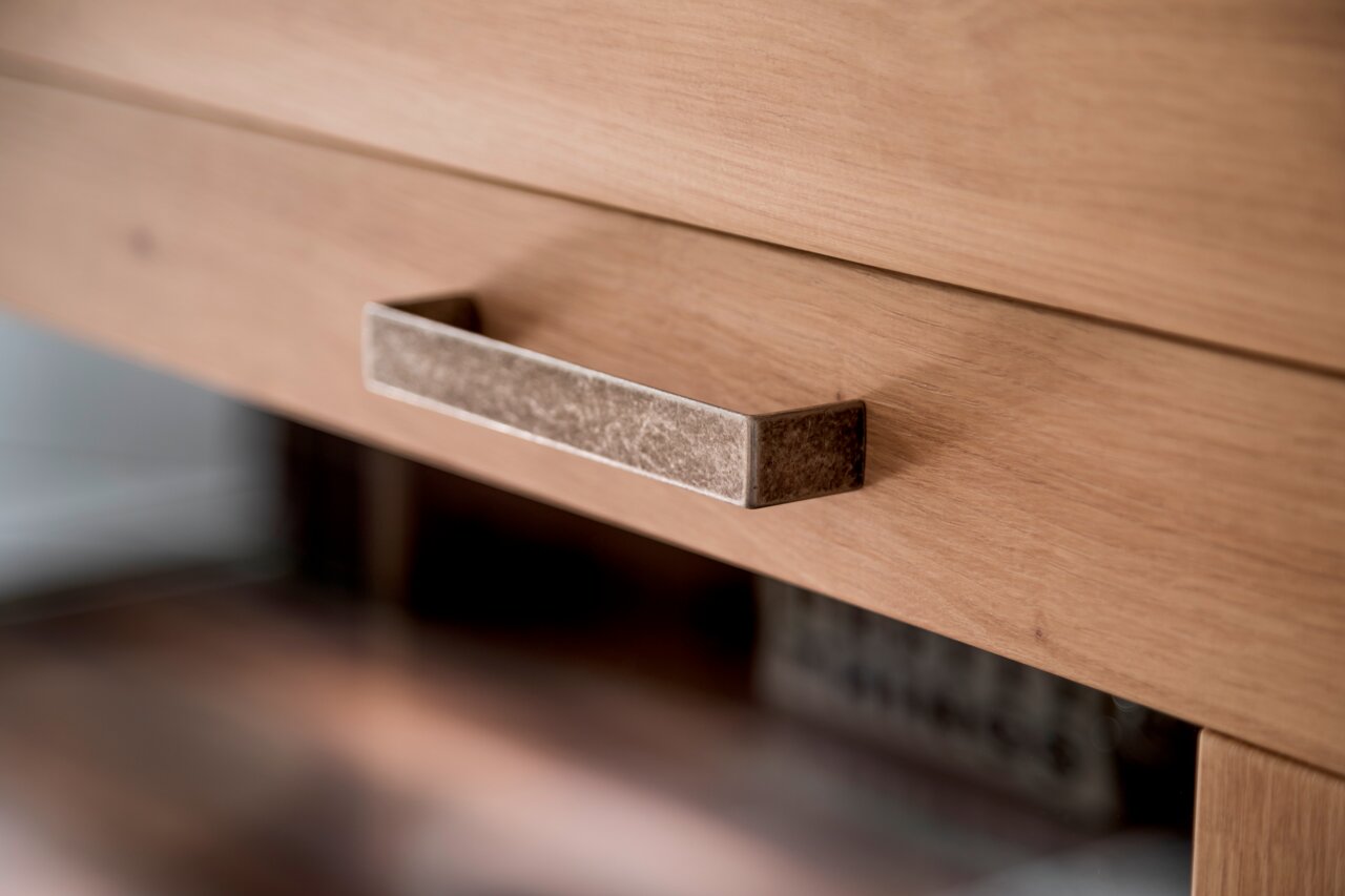 Nahaufnahme eines Holzschranks mit einem metallischen Griff, seitliche Perspektive