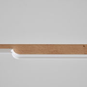 Nahaufnahme einer Kommode mit weißer Oberfläche und Holzleiste, seitliche Perspektive