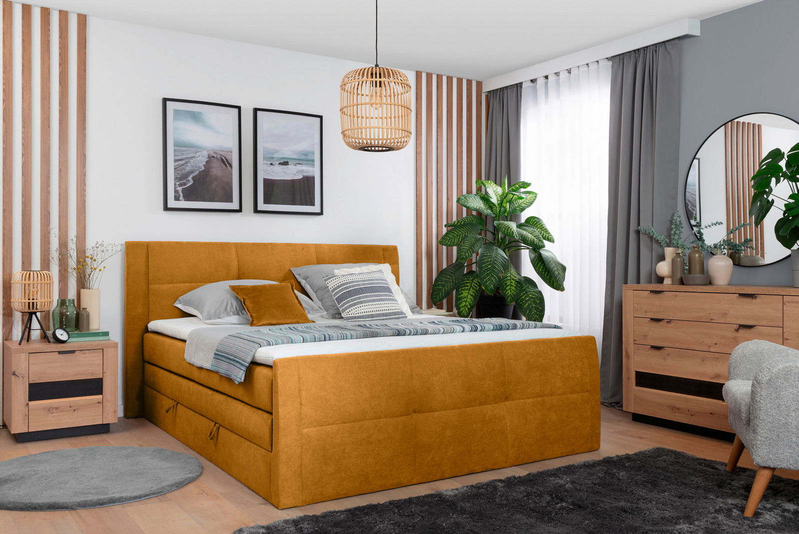 Gemütliches Schlafzimmer mit einem senfgelben Boxspringbett, umgeben von modernen Holzmöbeln und Pflanzen, aus der Perspektive von vorne rechts.