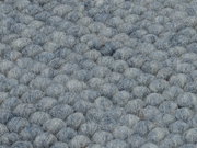 Nahaufnahme eines handgewebten Teppichs mit einer texturierten, grauen Oberfläche in Kugeloptik.