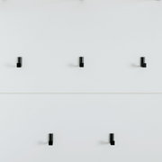 Garderobenpaneel mit sechs schwarzen Haken auf weißem Hintergrund, frontal betrachtet.