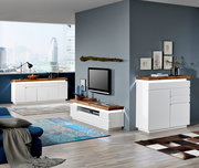 Modernes Wohnzimmer mit weißem TV-Lowboard und Sideboard, beide mit Holzoberfläche, in einer hellen, urbanen Umgebung. Perspektive von schräg vorne.