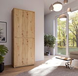 Hoher XL-Schuhschrank mit vier Türen aus hellem Holz, in einem modernen Raum mit großen Fenstern und Pflanzen, seitliche Perspektive.
