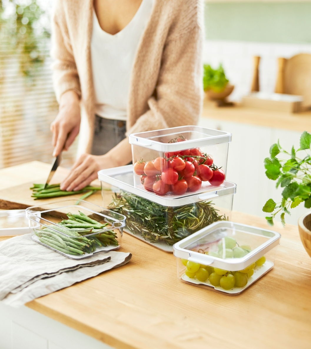 Kühlschrankorganizer 4-teilig, gefüllt mit frischem Gemüse und Obst, auf einer Küchenarbeitsplatte, seitliche Perspektive