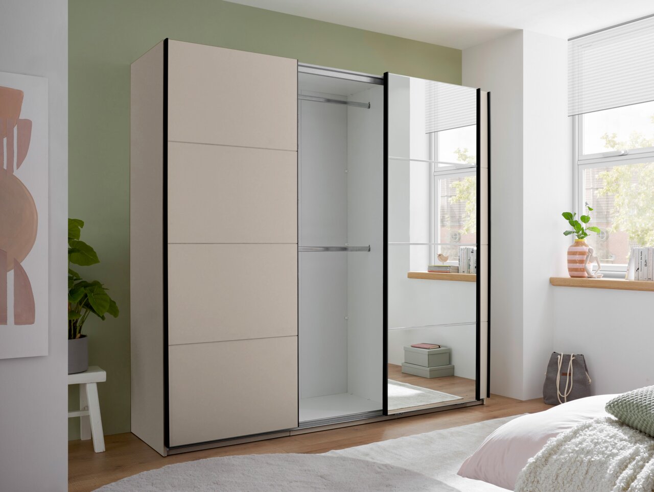 Moderner Schwebetürenschrank in Beige mit einer Spiegeltür und schwarzem Rahmen, eine Tür geöffnet mit Blick in den leeren Innenraum, im Schlafzimmer aus frontaler Perspektive.