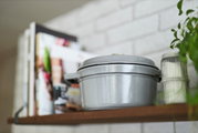 Grauer runder Bräter Cocotte 24cm auf einem Regal, seitliche Perspektive