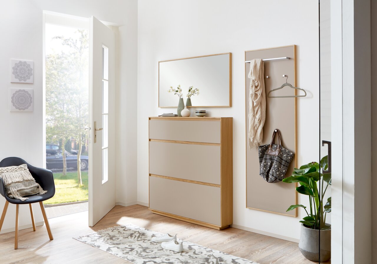Moderne Garderobeneinrichtung mit Schuhschrank, Spiegel und Garderobenpaneel in einem hellen Flur. Perspektive von vorne.
