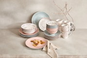 Porzellan-Set Valencia 30-teilig in sanften Pastelltönen, bestehend aus Tellern, Schalen und Tassen, auf einer neutralen Oberfläche arrangiert. Frontalansicht.