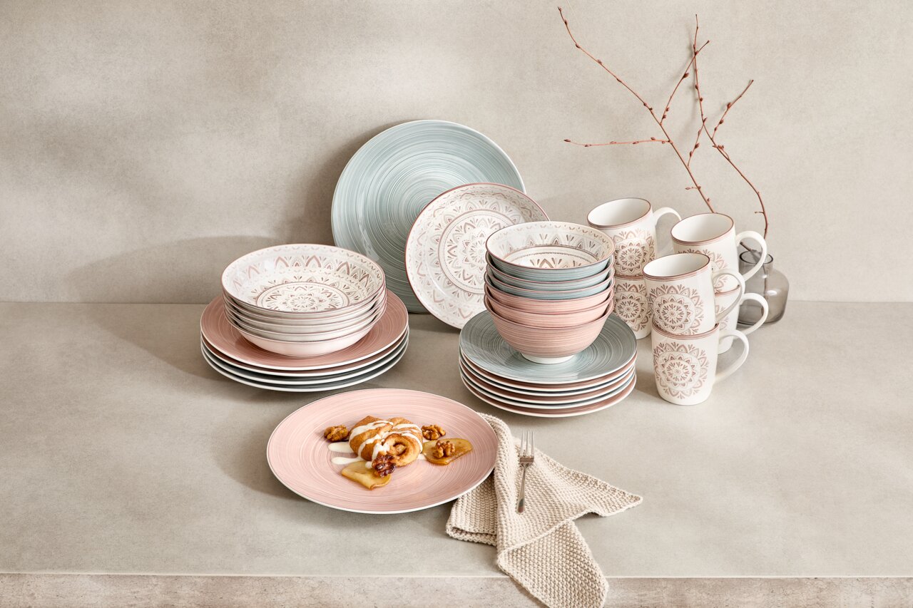 Porzellan-Set Valencia 30-teilig in sanften Pastelltönen, bestehend aus Tellern, Schalen und Tassen, auf einer neutralen Oberfläche arrangiert. Frontalansicht.