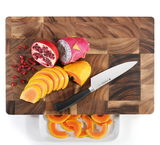 Vogelperspektive auf einen Hackblock aus Akazienholz mit geschnittenem Obst und einem Messer.