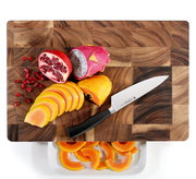 Vogelperspektive auf einen Hackblock aus Akazienholz mit geschnittenem Obst und einem Messer.