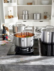 Bratentopf 16 cm aus Edelstahl auf einem Herd, gefüllt mit Gemüse, in einer modernen Küche, seitliche Perspektive.