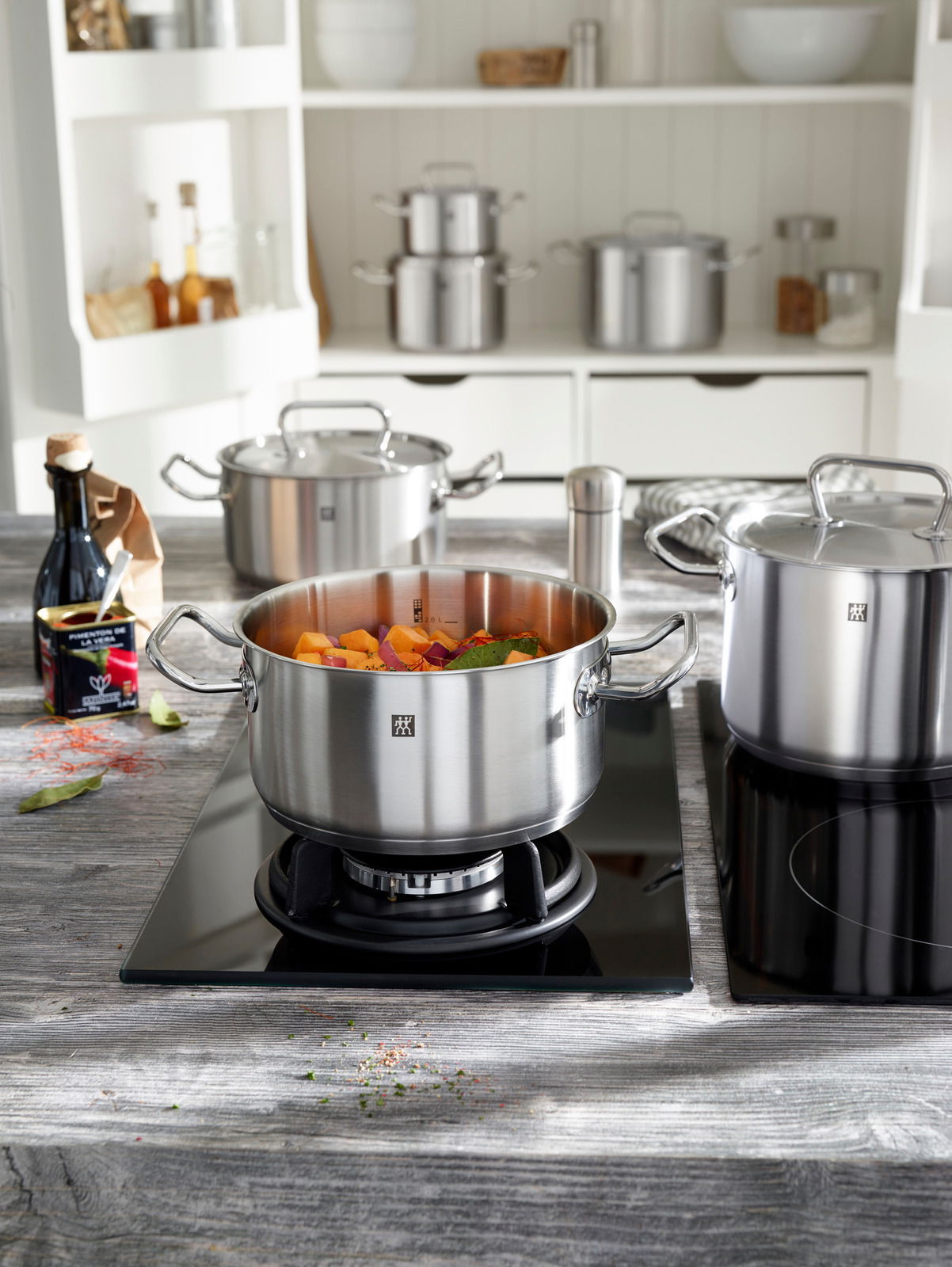 Bratentopf 16 cm aus Edelstahl auf einem Herd, gefüllt mit Gemüse, in einer modernen Küche, seitliche Perspektive.