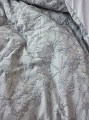 Nahaufnahme einer grauen Bettwäsche mit floralem Muster, aus der Vogelperspektive fotografiert.