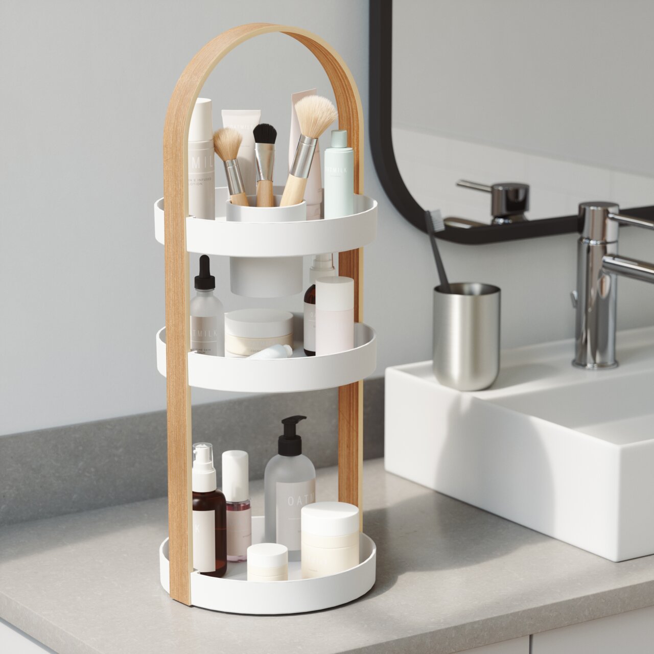 Drie verdiepingen tellende cosmetica-opberger met houten handvat, gevuld met diverse cosmeticaproducten, op een badkamerplank naast een wastafel, gezien vanuit de zijkant.