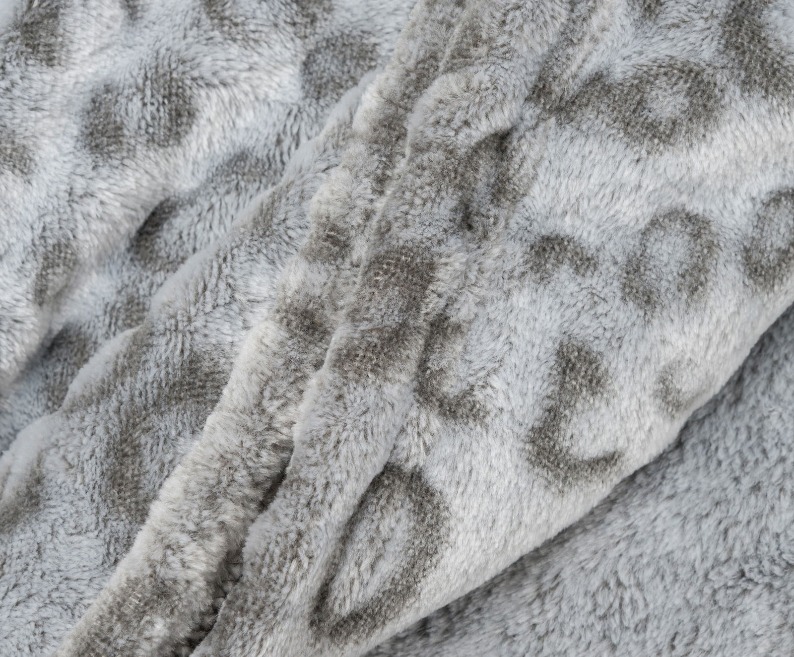 Nahaufnahme einer flauschigen, grauen Wohndecke mit dezentem Muster.