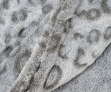 Nahaufnahme einer flauschigen, grauen Wohndecke mit dezentem Muster.