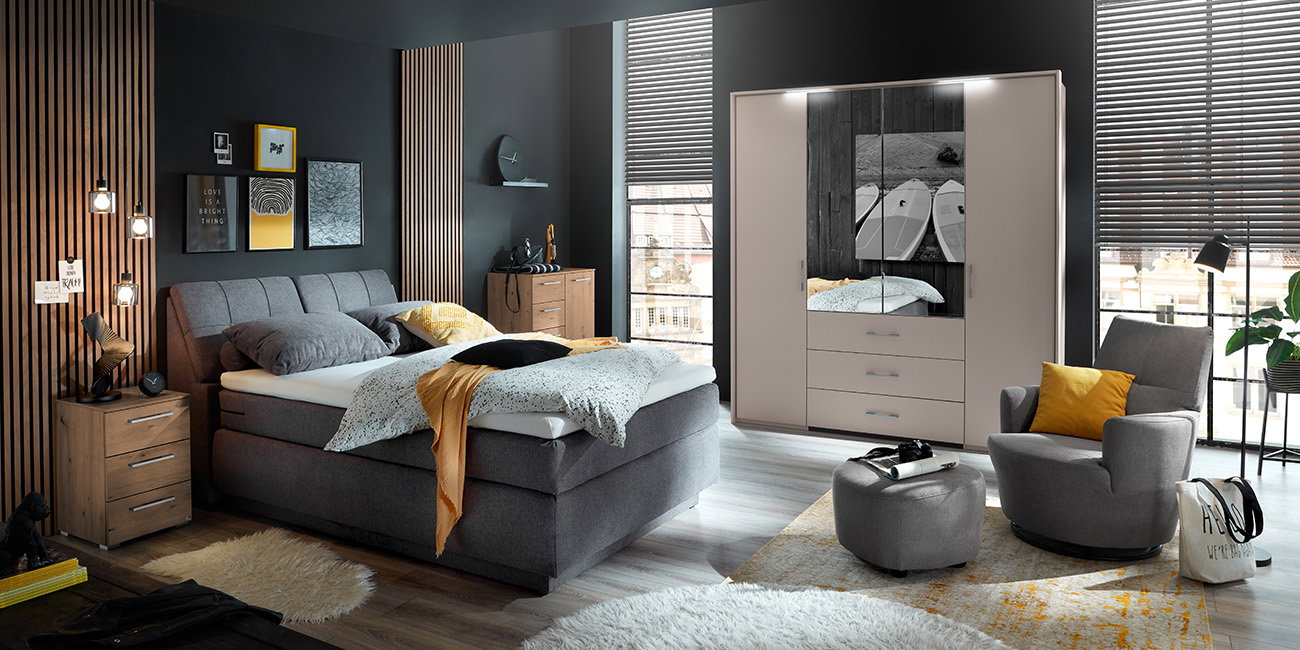 Ein Schlafzimmer mit dunkelgrauem Bett und weißen Kleiderschrank.