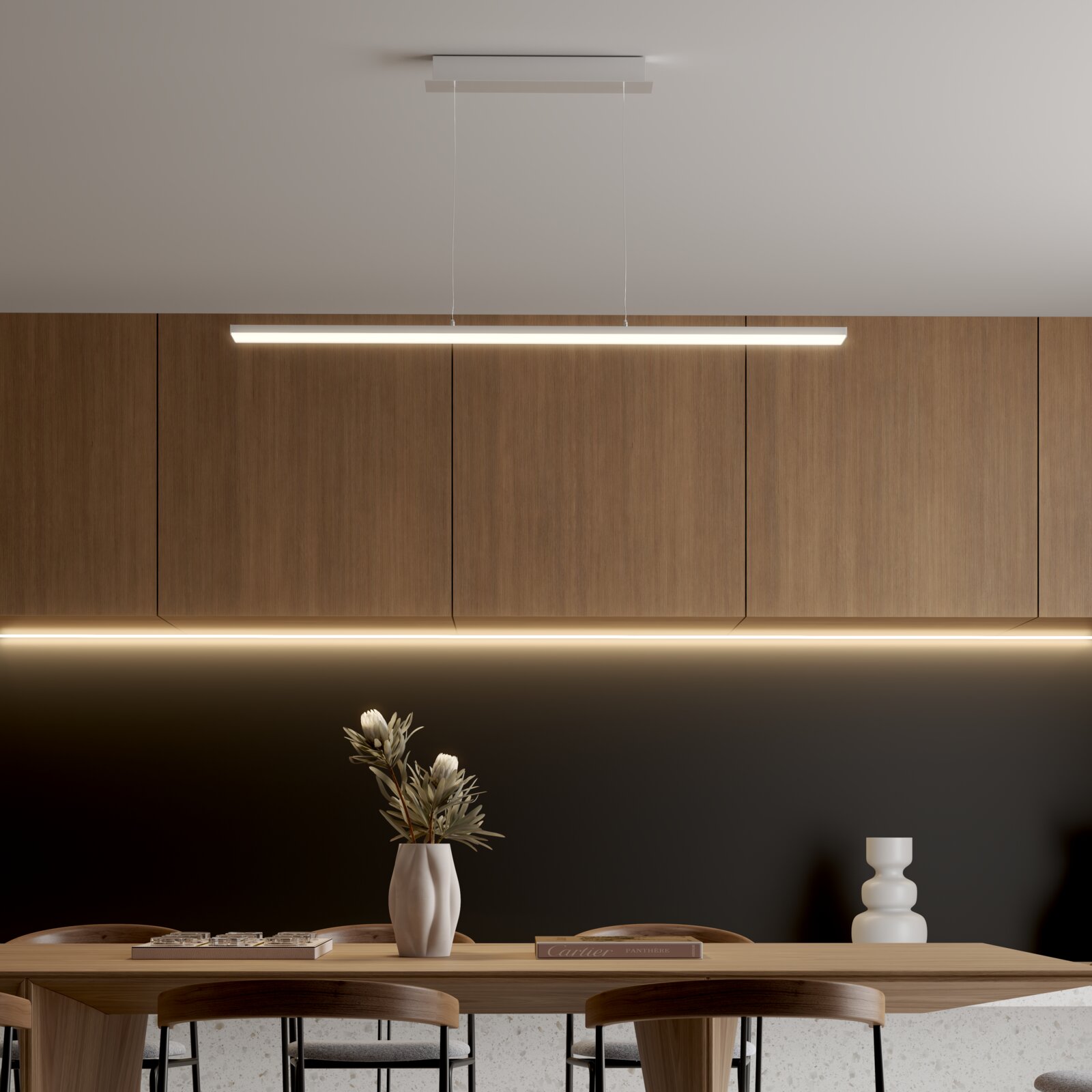 Moderne, strakke LED-hanglamp in wit met warmwit licht boven een eettafel voor houten kasten, gezien van voren.