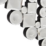 Nahaufnahme eines dekorativen Spiegels mit facettierten, runden und quadratischen Glaselementen auf schwarzem Hintergrund, perspektivisch von der Seite aufgenommen.