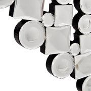 Nahaufnahme eines dekorativen Spiegels mit facettierten, runden und quadratischen Glaselementen auf schwarzem Hintergrund, perspektivisch von der Seite aufgenommen.