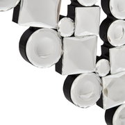 Nahaufnahme eines dekorativen Spiegels mit facettierten, runden und quadratischen Glaselementen auf schwarzem Hintergrund, perspektivisch von der Seite aufgenommen.