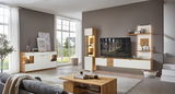 Moderne Wohnzimmermöbelkombination in heller, geräumiger Umgebung mit Sideboard, Highboard und TV-Wand in Holz- und Weißtönen, seitliche Perspektive.