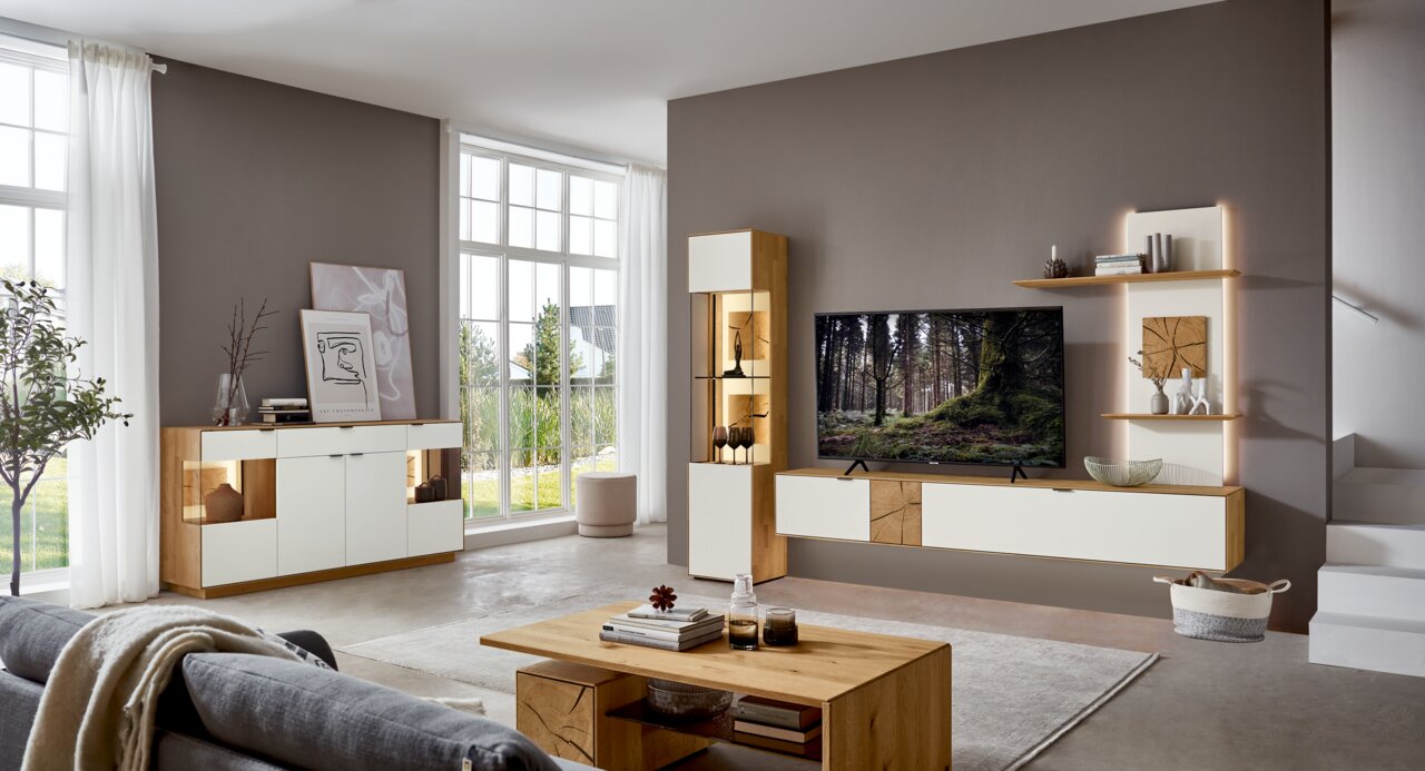 Moderne woonkamermeubelcombinatie in een lichte, ruime omgeving met dressoir, hoogkast en tv-wand in hout- en wittinten, zijaanzicht.