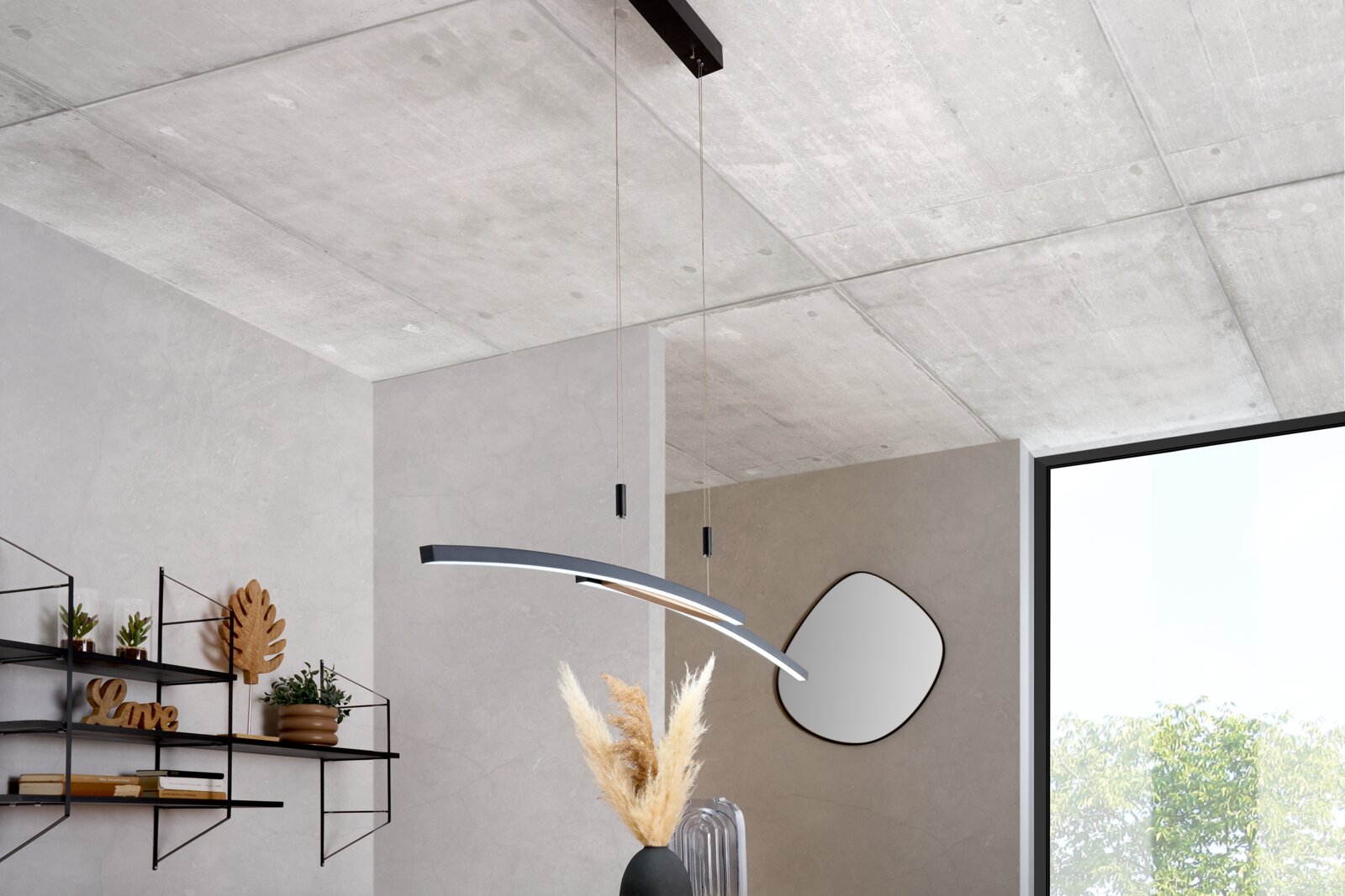 Moderne, gebogene LED-Pendelleuchte in Schwarz und Silber mit warmweißem Licht, an dünnen Seilen von der Decke abgehängt, in einem minimalistischen Wohnraum; Perspektive: leicht von unten im Raum nach oben zur Decke fotografiert.